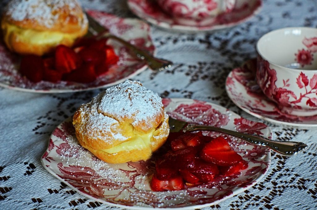 Cream puff with strawberries on a pink and white vintage plate