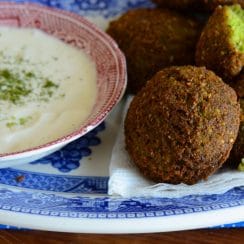 Falafel on a blue plate with dipping sauce