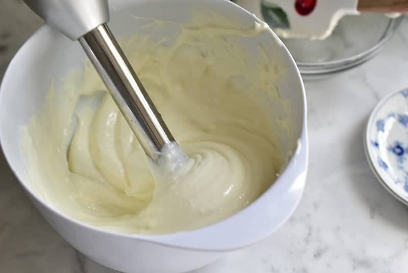 An immersion blender smooths ashta cream in a white bowl, Maureen Abood