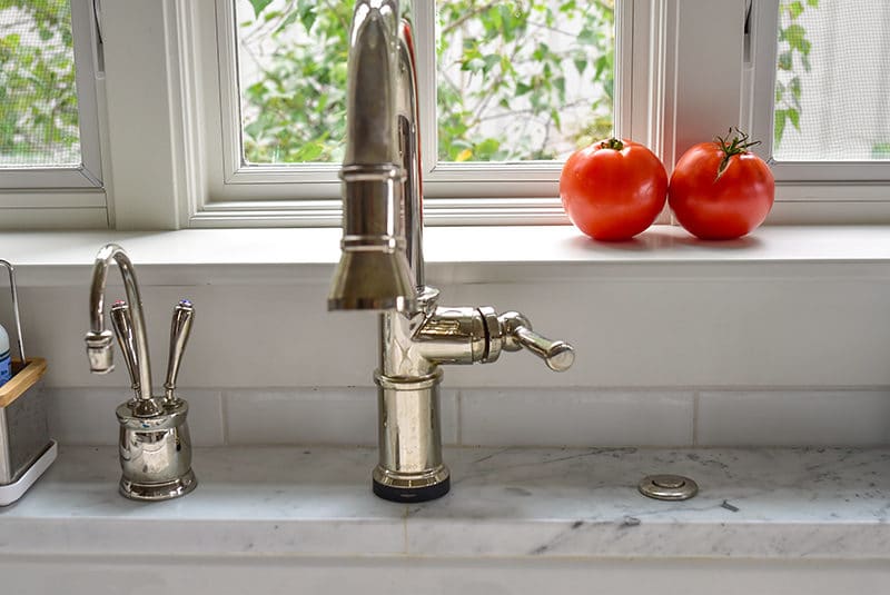 Two red tomatoes on a white kitchen windowsill behind the faucet, Maureen Abood
