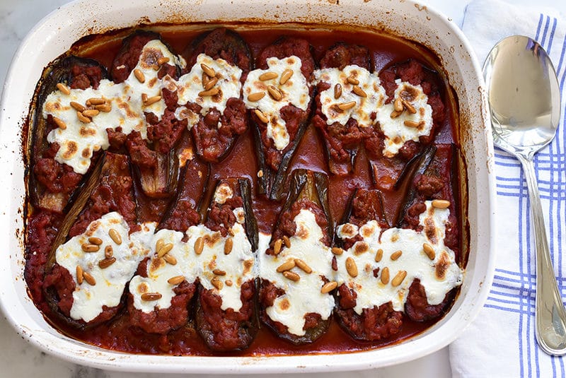 Lebanese eggplant boats in tomato sauce topped with cheese and pine nuts, in a white casserole, Maureen Abood