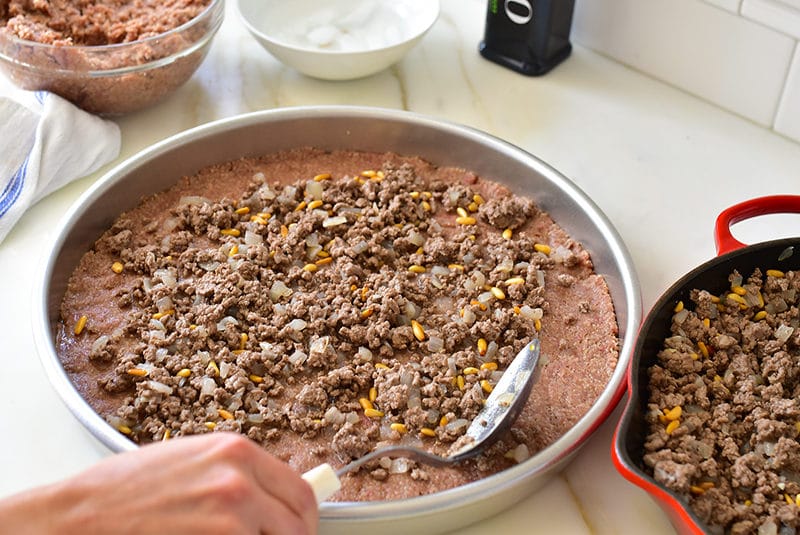 Filling spooned over the bottom layer of Lebanese kibbeh sahnieh