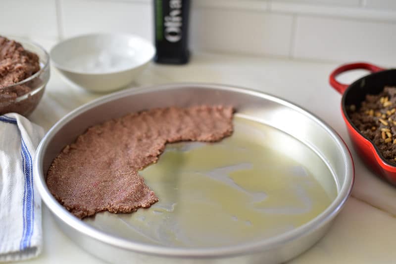 Kibbeh being layered in a big round pan