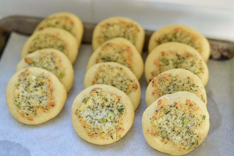 Mini cheese flatbreads lined up on a sheet pan