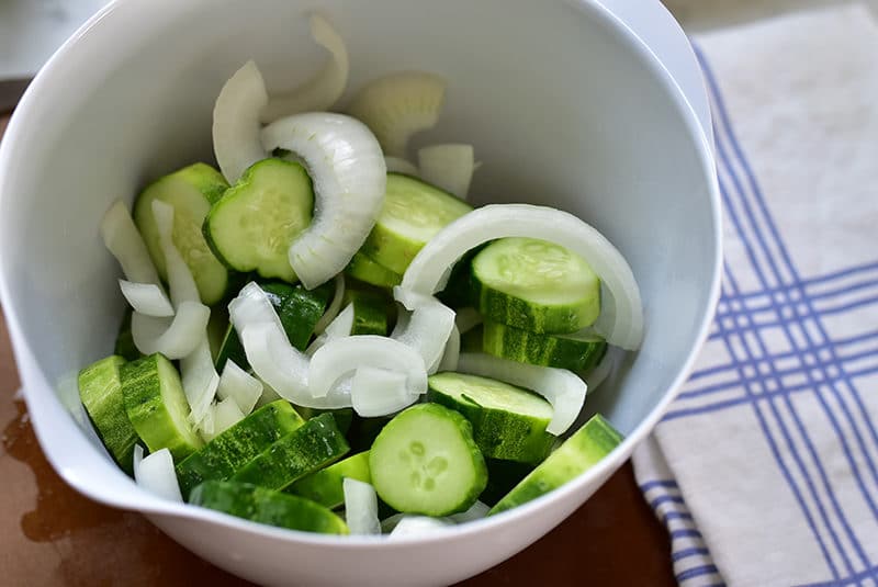 Slices of cucumbers and onion in a white bowl