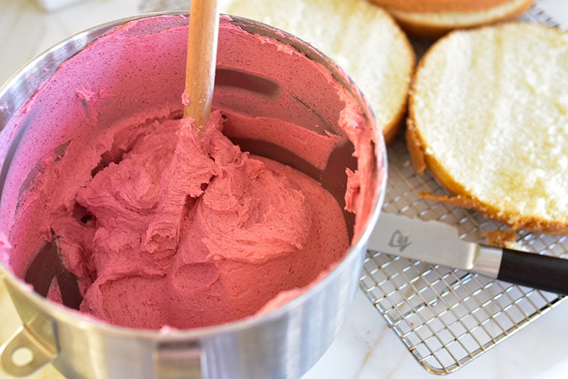 Raspberry buttercream with spatula in the mixer bowl