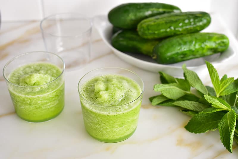Mint, cucumber slushie on the counter with fresh mint and cucumbers