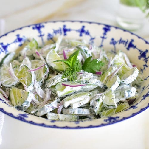 Cucumber salad with herbs in a blue and white bowl