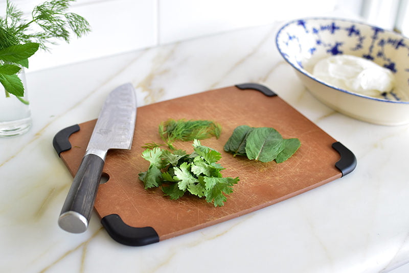 Fresh herbs on a cutting board with a sharp knife