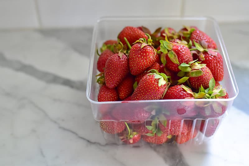 Strawberries in a plastic basket on the marble counter