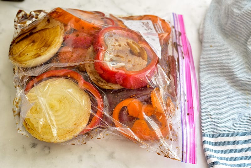 Plastic bag filled with flank steak, peppers, and pomegranate marinade