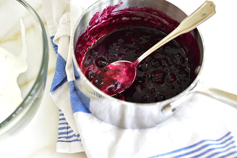 Blueberry sauce in a sucepan with a blue and white towel