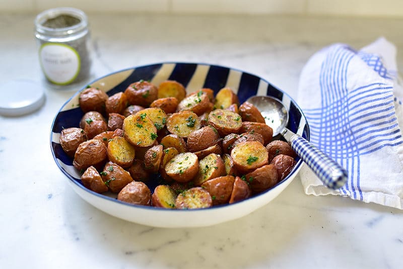 Roasted New Potatoes in a blue striped bowl with a jar of mint salt