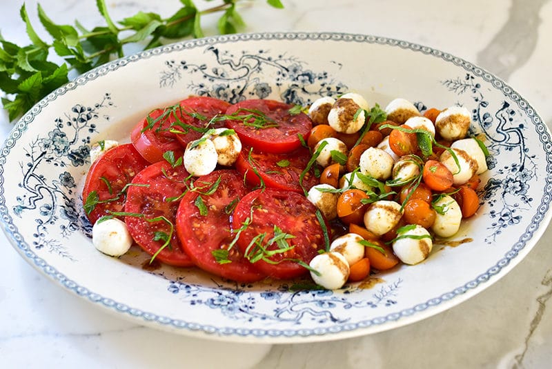 Tomato slices and mozzarella balls on a blue platter