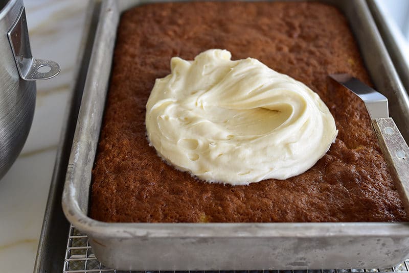 Dollop of cream cheese frosting on a carrot cake in a sheet pan