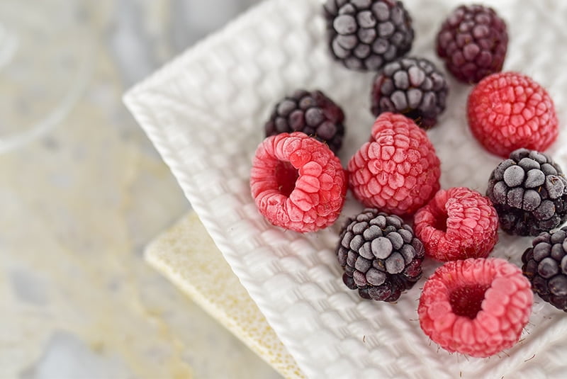 Frozen raspberries and blackberries on a white plate