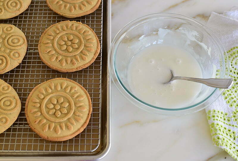 Molded shortbread cookies on a rack with a bowl of icing