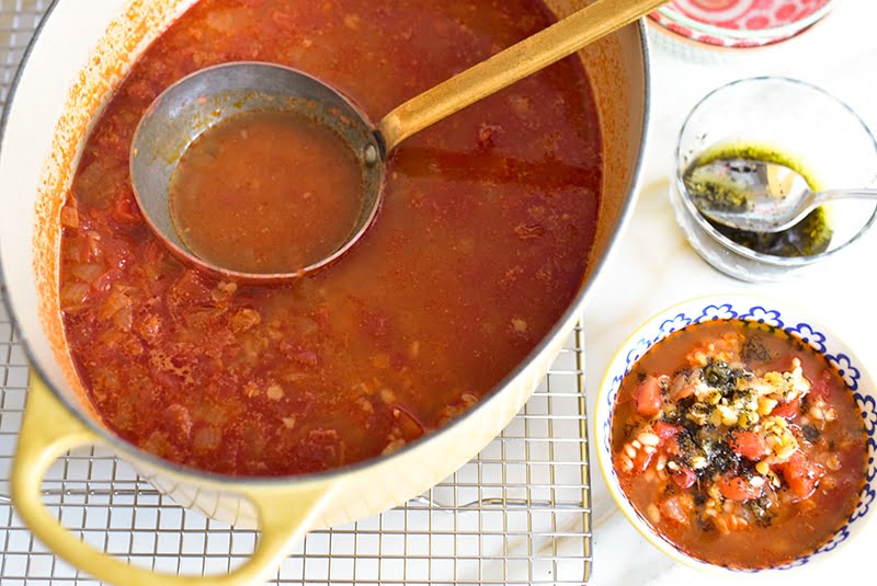 Tomato bulgur lentil soup in a yellow pot with a ladle