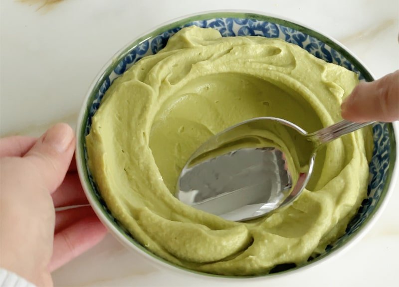 Avocado hummus with a spoon in a blue bowl