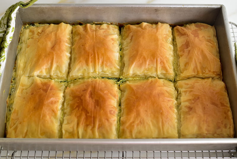 Easier spanakopita with golden cut pieces in a pan