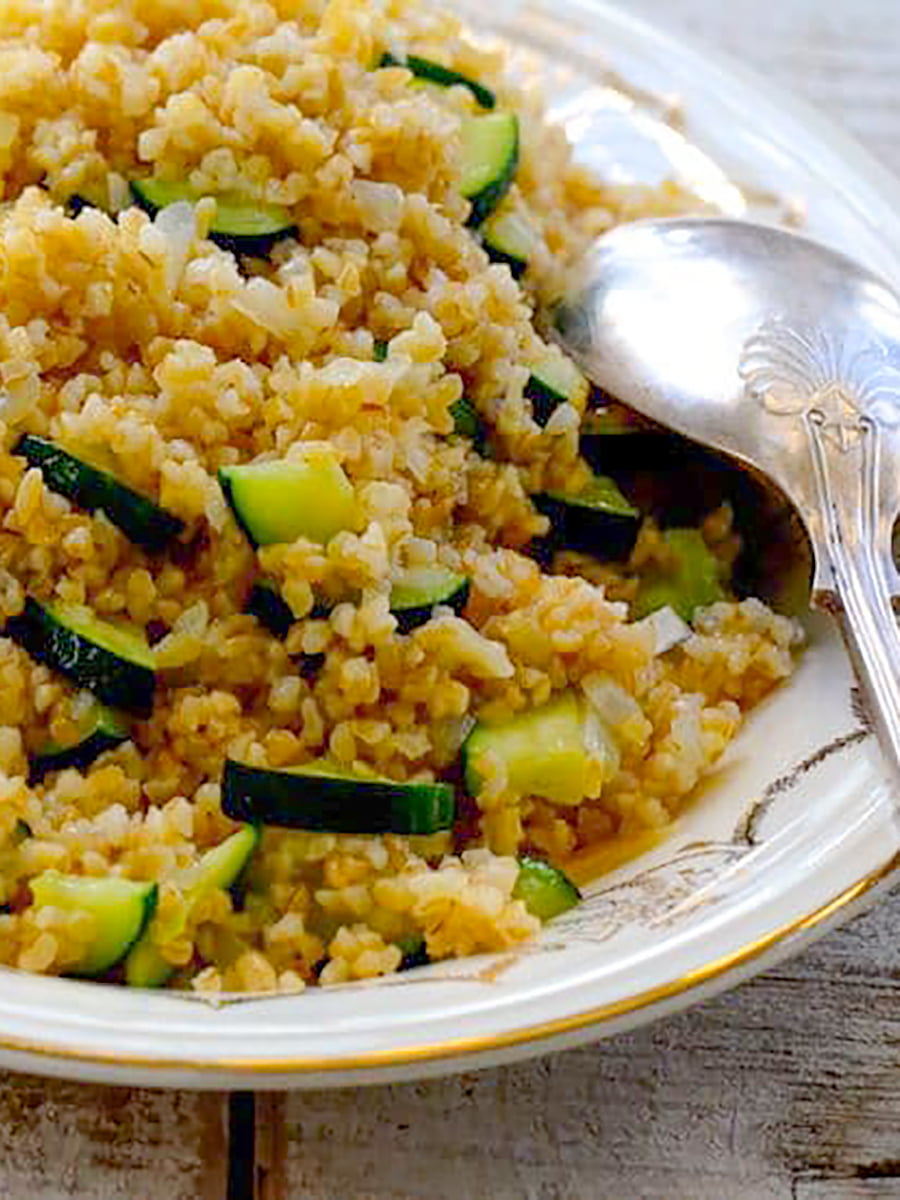 Bulgur Pilaf with zucchini on a platter with a silver spoon