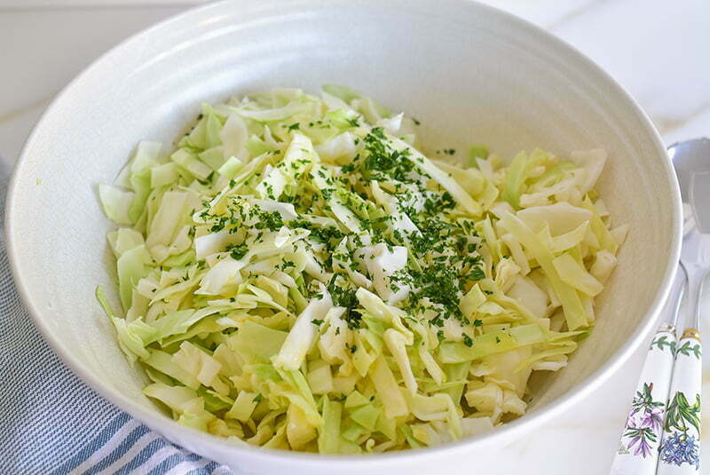 Big bowl of shredded cabbage with chopped cilantro on top for salad