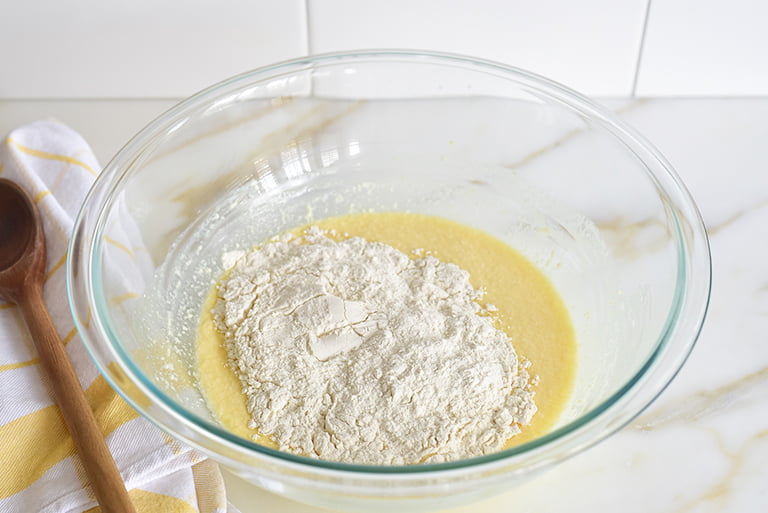 Flour with batter for soft glazed cinnamon rolls in a bowl