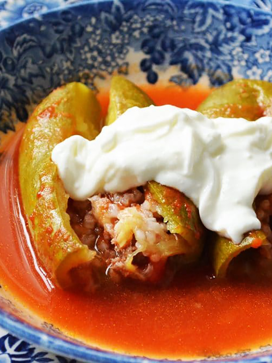Stuffed koosa in tomato sauce with labneh on top in a blue bowl